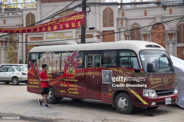 Tourist walks past a shuttle bus for the Oriental Pearl casino in Sihanoukville, Cambodia, on Saturday, March 31, 2018. It's against the law for...