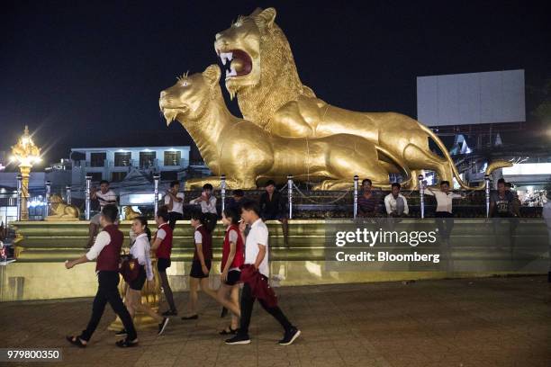 Casino workers walk past the Golden Lions roundabout at night in Sihanoukville, Cambodia, on Friday, March 30, 2018. It's against the law for...