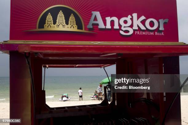 Tourist, seen through a booth advertising Angkor Beer, stands near a jet ski on Ochheuteal Beach in Sihanoukville, Cambodia, on Saturday, March 31,...