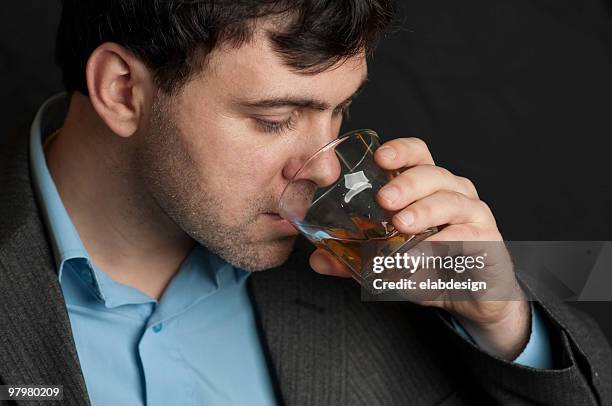 man drinking from a glass of whiskey - human mouth stockfoto's en -beelden