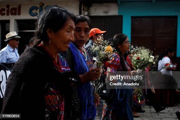 Guatemalan indigenous women carry flowers, as a truck transporting the 172 urns containing the remains of victims of the Guatemalan armed conflict ,...