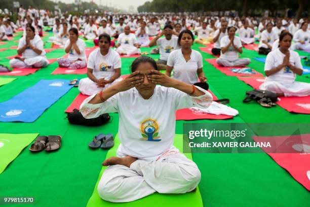 Practitioners take part in a mass yoga session on International Yoga Day at Rajpath in New Delhi on June 21, 2018. - Downward-facing dogs, cobras and...