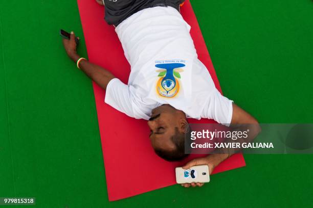 Practitioner rests on his mat as he takes part in a mass yoga session on International Yoga Day at Rajpath in New Delhi on June 21, 2018. -...