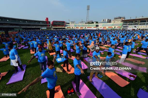 Practitioners participate in a mass session to mark International Yoga Day in Dhaka on June 21, 2018. - Downward-facing dogs, cobras and warriors...