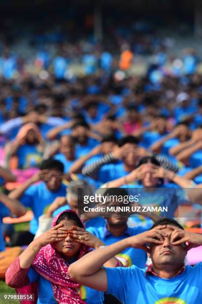Practitioners participate in a mass session to mark International Yoga Day in Dhaka on June 21, 2018. - Downward-facing dogs, cobras and warriors...