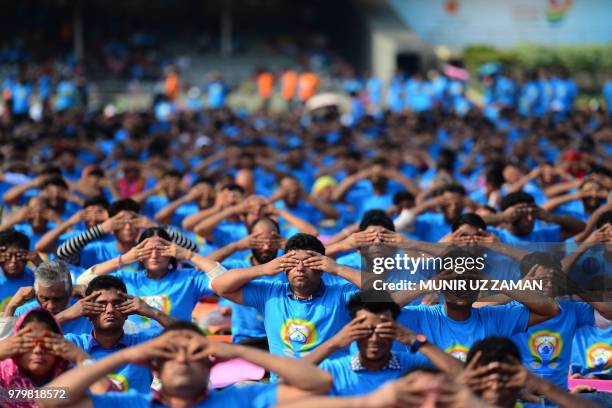 Practitioners participate in a mass session to mark International Yoga Day in Dhaka on June 21, 2018. - Downward-facing dogs, cobras and warriors...