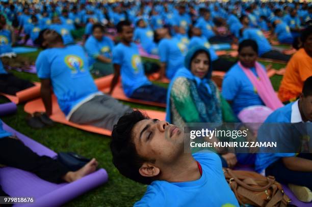 Practitioners participate in a mass session to mark International Yoga Day in Dhaka on June 21, 2018. - Downward-facing dogs, cobras and warriors...