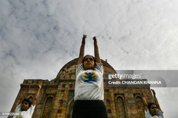Indian instructors perform during a mass yoga session to mark International Yoga Day next to a Mughal-era tomb in Lodi Gardens in New Delhi on June...