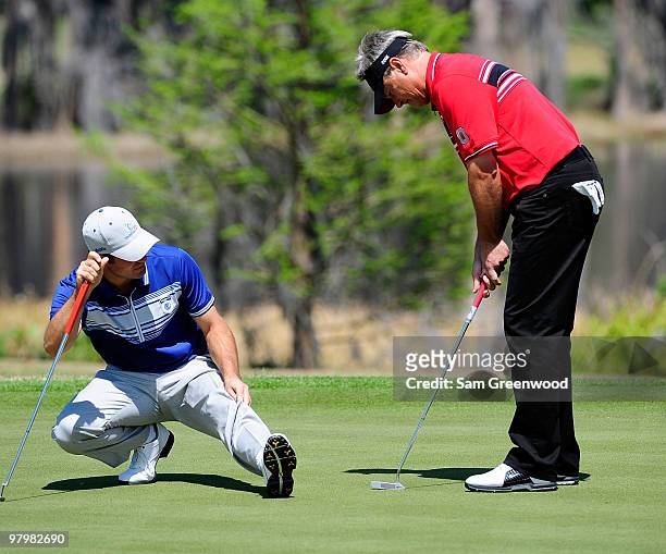 Trevor Immelman of South Africa and John Cook wait to play a shot on the 9th hole during the second day's play of the Tavistock Cup at Isleworth Golf...
