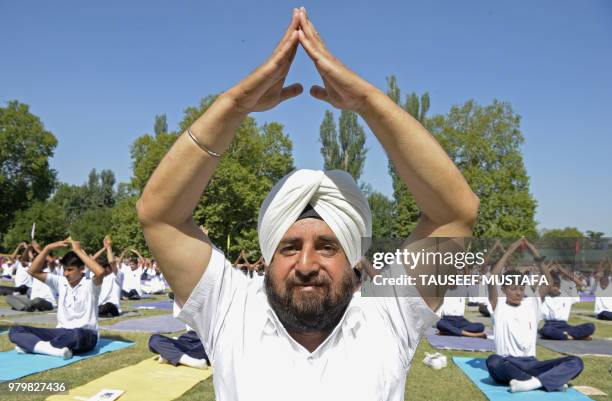 Jammu and Kashmir Police officer takes part in a yoga session with Indian Kashmiri students of the National Cadet Corps to mark International Yoga...