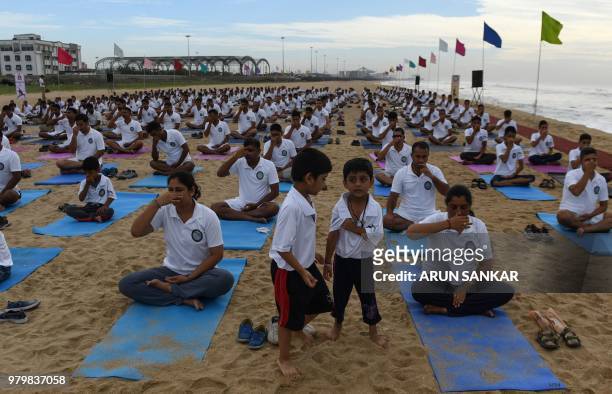 Children gather next to Indian Naval Cadets taking part in a yoga session to mark International Yoga Day in Chennai on June 21, 2018. -...