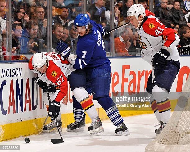 Garnet Exelby of the Toronto Maple Leafs battles for the puck with Michael Frolik and Shawn Matthias of the Florida Panthers during game action March...