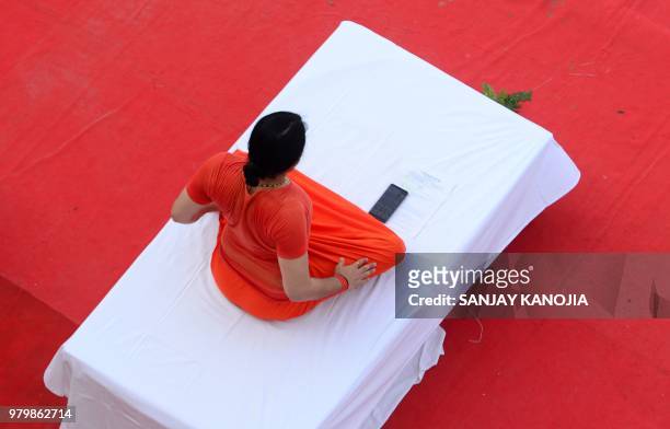 An Indian yoga guru takes part in a mass yoga session on International Yoga Day in Allahabad on June 21, 2018. - Downward-facing dogs, cobras and...