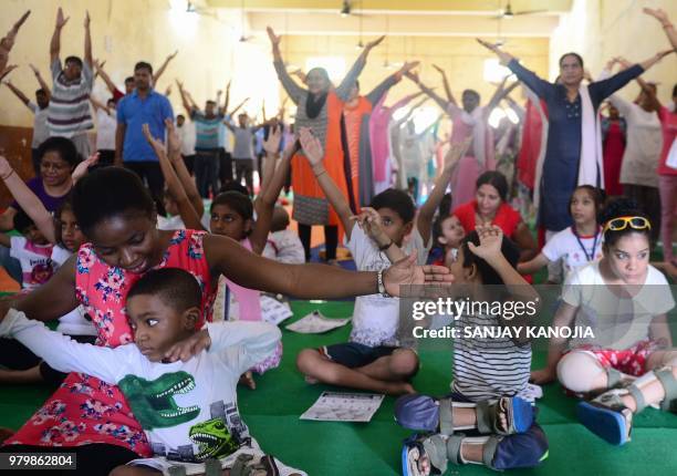 Indian children with cerebral palsy take part in a yoga session on International Yoga Day in Allahabad on June 21, 2018. - Downward-facing dogs,...