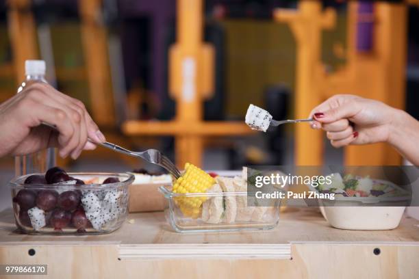 chinese man and woman eating healthy food on a break in a gym - aerobics instructor stock pictures, royalty-free photos & images