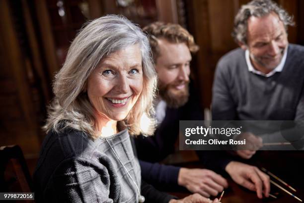 portrait of smiling senior woman playing mikado with husband and adult son - mikado stock pictures, royalty-free photos & images