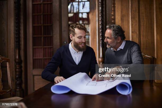 younger and older man discussing floor plan on wooden table - successor stock pictures, royalty-free photos & images