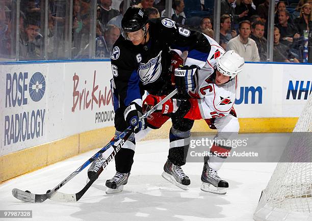 Kurtis Foster of the Tampa Bay Lightning fights off a check by Eric Staal of the Carolina Hurricanes at the St. Pete Times Forum on March 23, 2010 in...