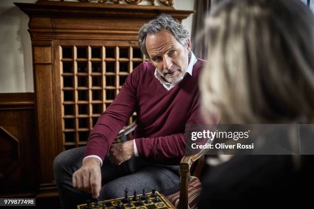 grey-haired man playing chess with his wife - schachbrett stock-fotos und bilder
