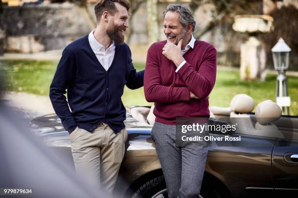 happy father and adult son at convertible car - welvaart stockfoto's en -beelden