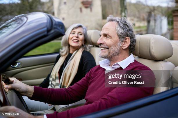 happy grey-haired couple in convertible car - welvaart stockfoto's en -beelden