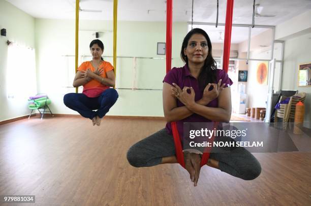 Indian aerial yoga instructor Pratibha Agarwal demonstrates aerial yoga at her studio on International Yoga Day in Hyderabad on June 21, 2018. -...