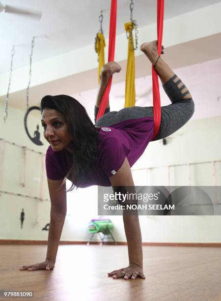 Indian aerial yoga instructor Pratibha Agarwal demonstrates aerial yoga at her studio on International Yoga Day in Hyderabad on June 21, 2018. -...