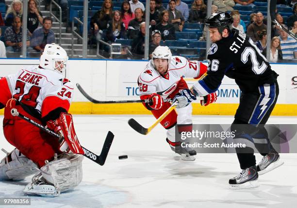 Martin St. Louis of the Tampa Bay Lightning shoots against Manny Legace of the Carolina Hurricanes as Jamie McBain defends at the St. Pete Times...