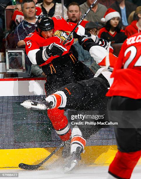Andy Sutton of the Ottawa Senators throws a big hit on Darroll Powe of the Philadelphia Flyers in a game at Scotiabank Place on March 23, 2010 in...
