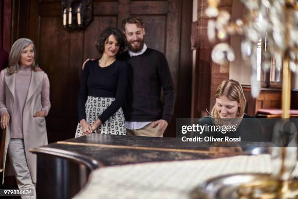 young woman playing piano watched by her family - sister act stock pictures, royalty-free photos & images