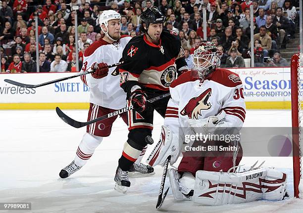 Adam Burish of the Chicago Blackhawks and Derek Morris of the Phoenix Coyotes approach goalie Ilya Bryzgalov as they chase the puck during the game...