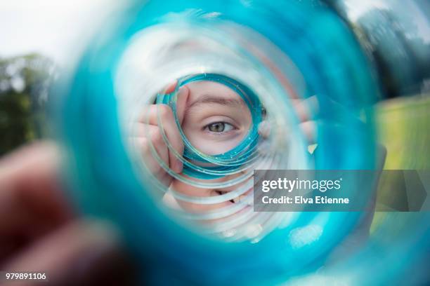 teenage girl looking through a blue coiled slinky toy - see through photos et images de collection