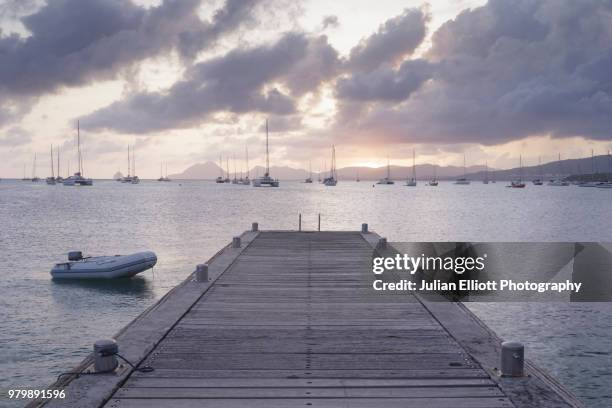 sunset from the village of sainte anne on the island of martinique. - wood pier stock pictures, royalty-free photos & images