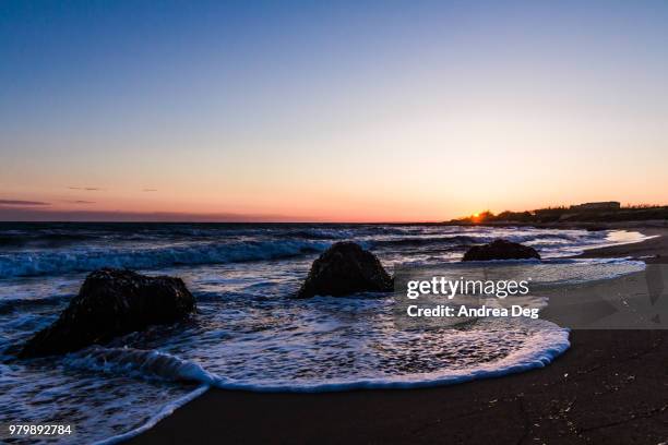 sunset over sandy beach with rock formations, sicily, italy - portopalo di capo passero stock pictures, royalty-free photos & images