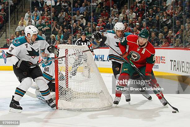 Andrew Brunette of the Minnesota Wild handles the puck with Kent Huskins and Niclas Wallin of the San Jose Sharks defending during the game at the...