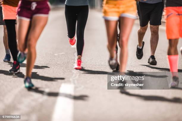 large group of unrecognizable marathon runners having a race on the road. - marathon feet stock pictures, royalty-free photos & images