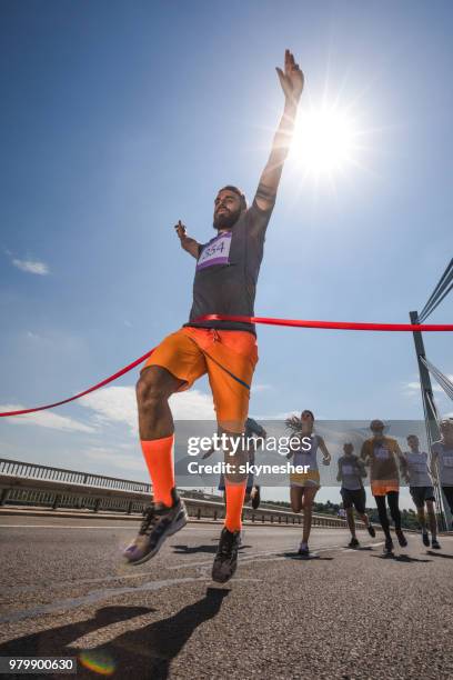 niedrigen winkel ansicht des erfolgreichen menschen überqueren der ziellinie auf marathon-rennen. - marathon ziel stock-fotos und bilder