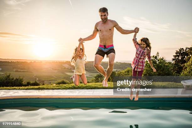 zorgeloos vader en zijn dochter plezier tijdens het springen in het zwembad. - jump dad stockfoto's en -beelden