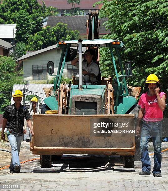 Laborers take a leave from work for their afternoon meal at a construction site in Kuala Lumpur on March 24, 2010. Amnesty International urged...