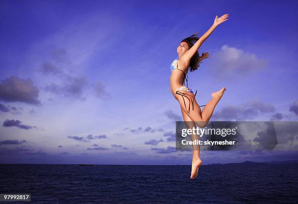 happy young woman is jumping in the beach - happy jumping stockfoto's en -beelden