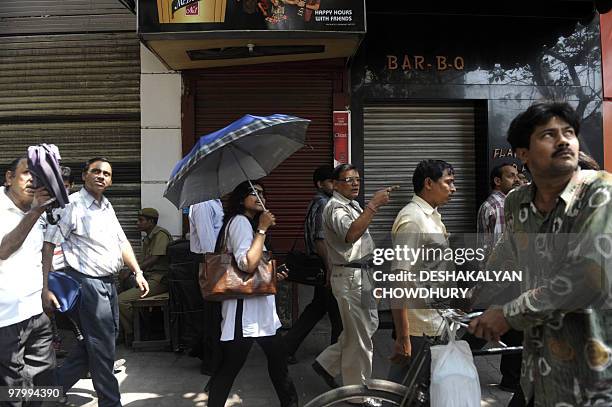 Indian passers-by look up at fire-damaged highrise in Kolkata on March 24, 2010. A giant fire engulfed a landmark building in the heart of the...