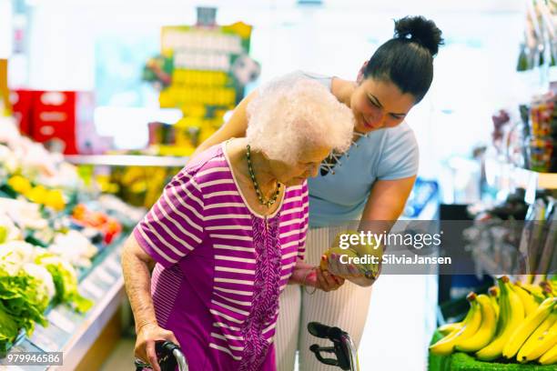 caregiver helping senior woman with shopping - senior women shopping stock pictures, royalty-free photos & images