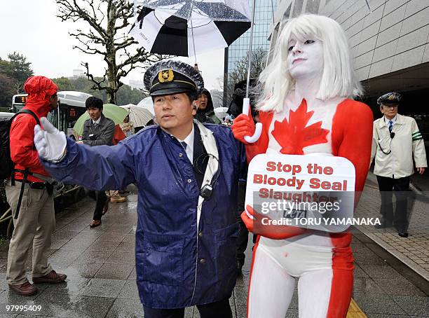 Policeman tries to remove female animal-rights activist Ashley Fruno , covered with a body-painting to look like the Canadian flag, during her...
