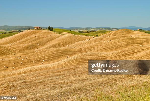 rolling rural landscape with haybales in field under clear blue sky, crete senesi, tuscany, italy - radice stock-fotos und bilder