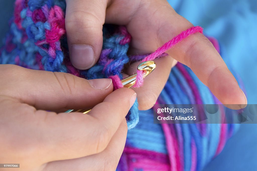 Primer plano de manos crocheting un edredón de pluma