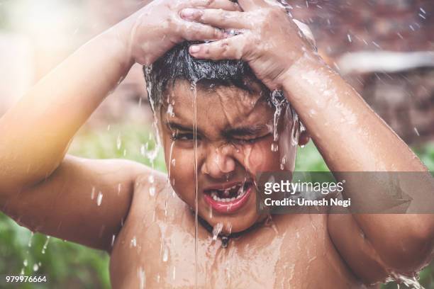 un giovane indiano fa il bagno sotto un rubinetto - village boy foto e immagini stock