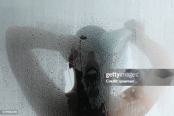 silhouette of woman taking shower behind steamy door - hot shower stockfoto's en -beelden