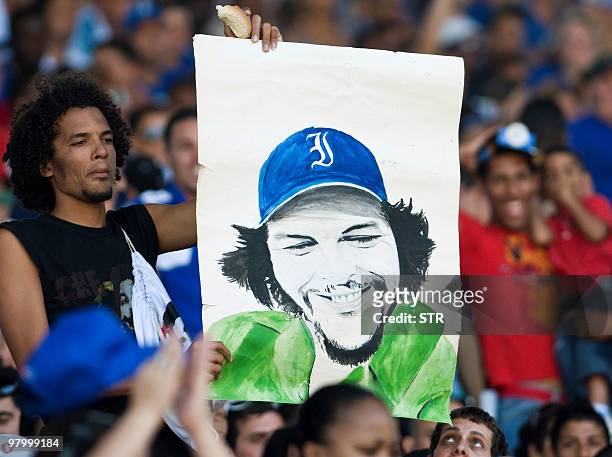 Baseball fan holds a drawing of guerrilla leader Ernesto "Che" Guevara, at the Latinoamericano stadium in Havana, on March 14, 2010 during the 49th...