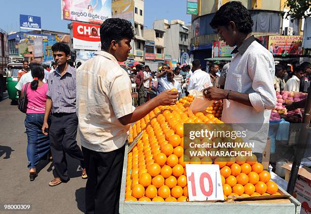 Sri Lankan street vendor sells oranges to a customer on a sidewalk in Colombo on March 15, 2010. Pavement hawking is illegal, yet many street...