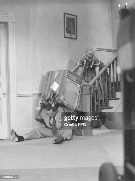 American comedienne Lucille Ball drops a tv set on Desi Arnaz in a clip from a television show, circa 1955.